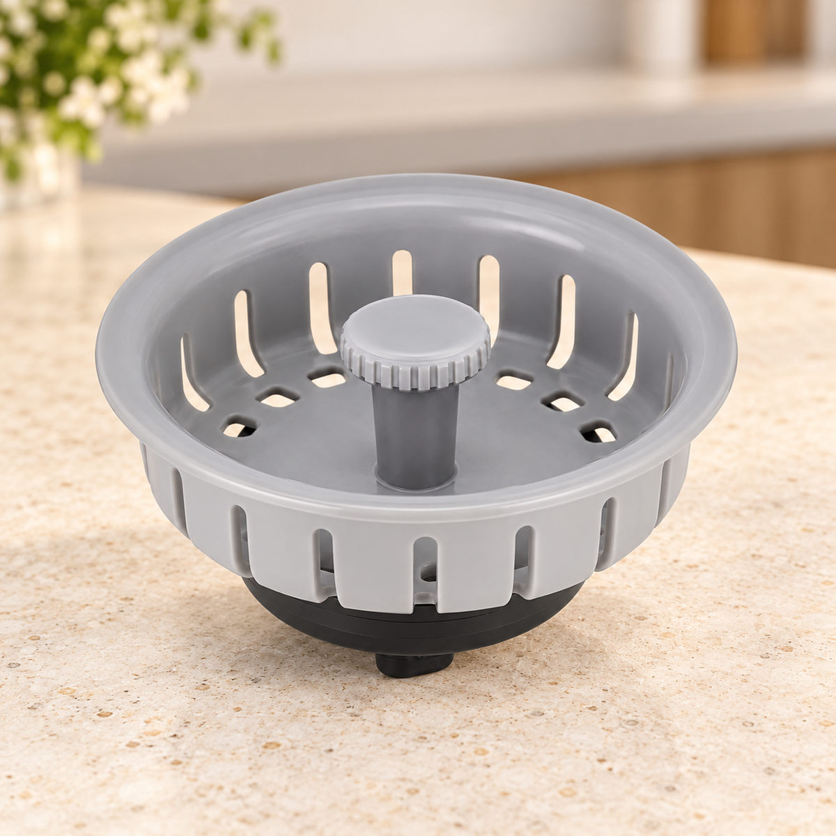 Filtro plástico para canastilla de lavaplatos de 4 pulgadas suelto sobre piedra cálida antes de instalar; accesorios del ambiente no incluidos.