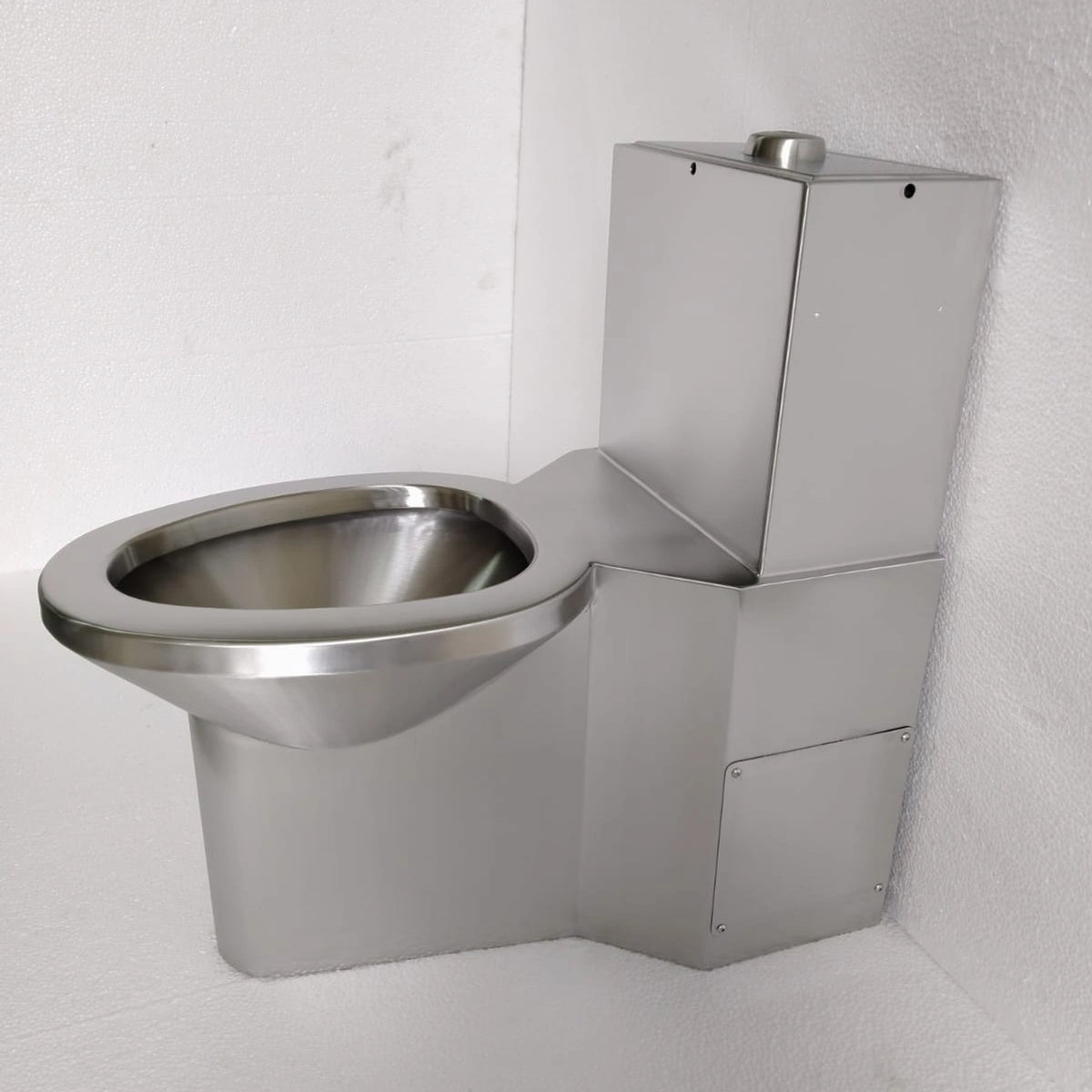 Sanitario monolítico antivandálico de acero inoxidable satinado, fotografía original con taza, tanque y faldón.