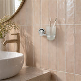 Portavaso mural de aluminio satinado con vaso de cristal ambientado en baño, vista cercana