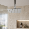 Cabezal de ducha cuadrado cromado instalado en baño moderno, con brazo visible solo como contexto