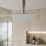 Cabezal de ducha cuadrado cromado instalado en baño moderno, con brazo visible solo como contexto