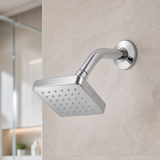 Set de ducha cuadrado cromado instalado en un baño moderno con cabezal, brazo y escudo visibles
