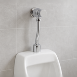 Fluxómetro temporizado instalado sobre un urinario en baño moderno