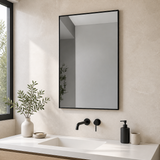 Espejo rectangular con marco metálico negro instalado en un baño moderno