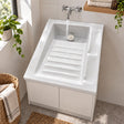Lavadero cerámico blanco 60 x 48 cm instalado sobre mueble con grifería mural en funcionamiento