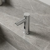 Detailed overhead view of a small chrome sensor faucet on textured bathroom countertop, highlighting its micro-texture and modern design.