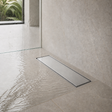 Desagüe de piso invisible de 30 x 10 cm instalado a ras en una ducha clara
