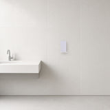 Secador de manos en aluminio instalado en la pared de un baño moderno (imagen ilustrativa)